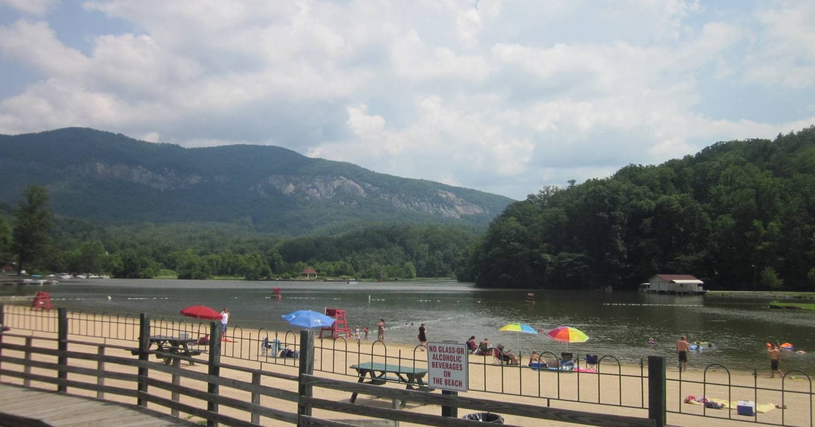 Lake Lure Beach with visitors on the sand and the mountains of Chimney Rock State Park in the background