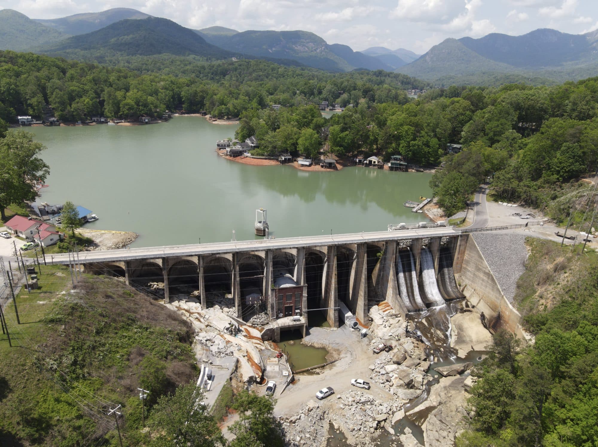 Aerial view of the Lake Lure dam and power station, with the lake behind it and mountains beyond