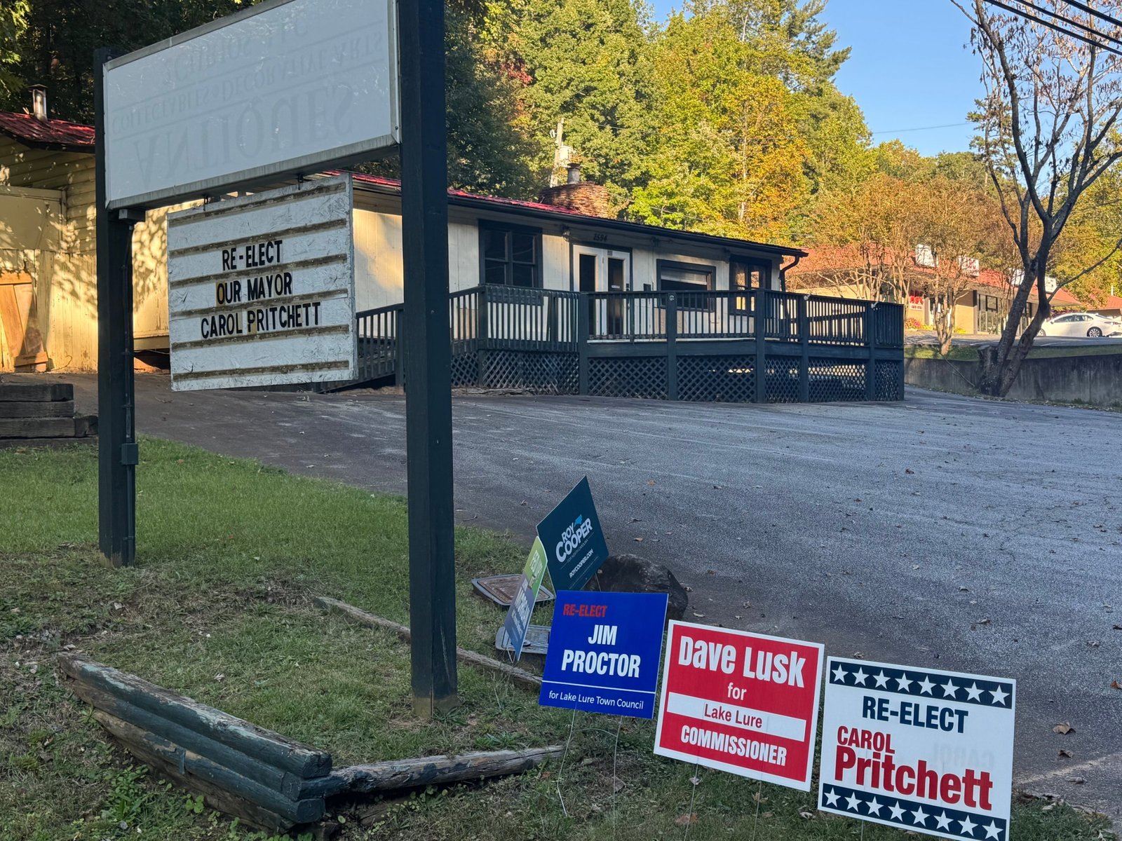 A vacant building's changeable-copy sign reading 'Re-elect our mayor Carol Pritchett', with yard signs below